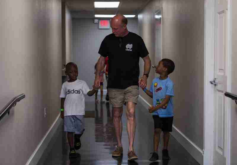 Children Walking with Volunteer Down Hallway